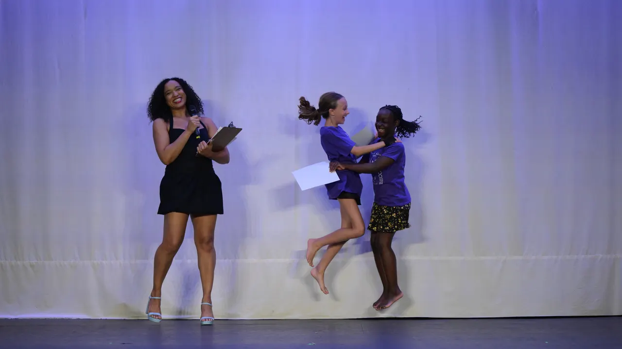 Two young dancers jumping for joy on stage