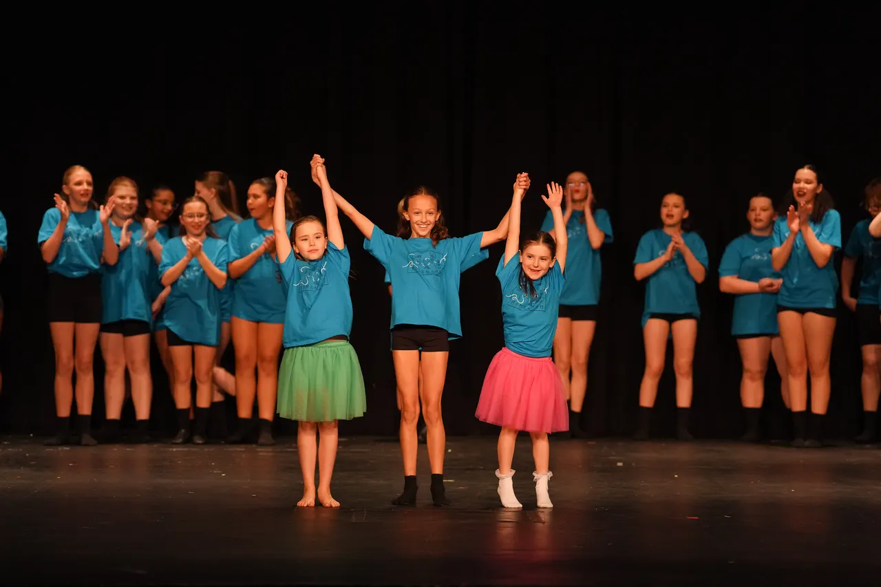 Young dancers cheering on stage at the end of a show